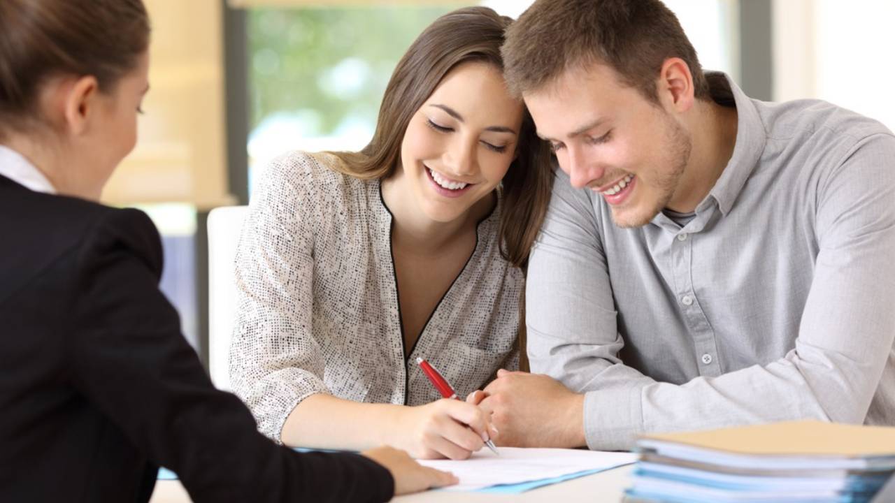 happy-couple-signing-a-contract-at-office-picture-id820868610.jpg